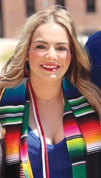 Alma Borunda-Granillo poses for a photo wearing her graduation regalia at commencement on Regis’ Northwest Denver campus