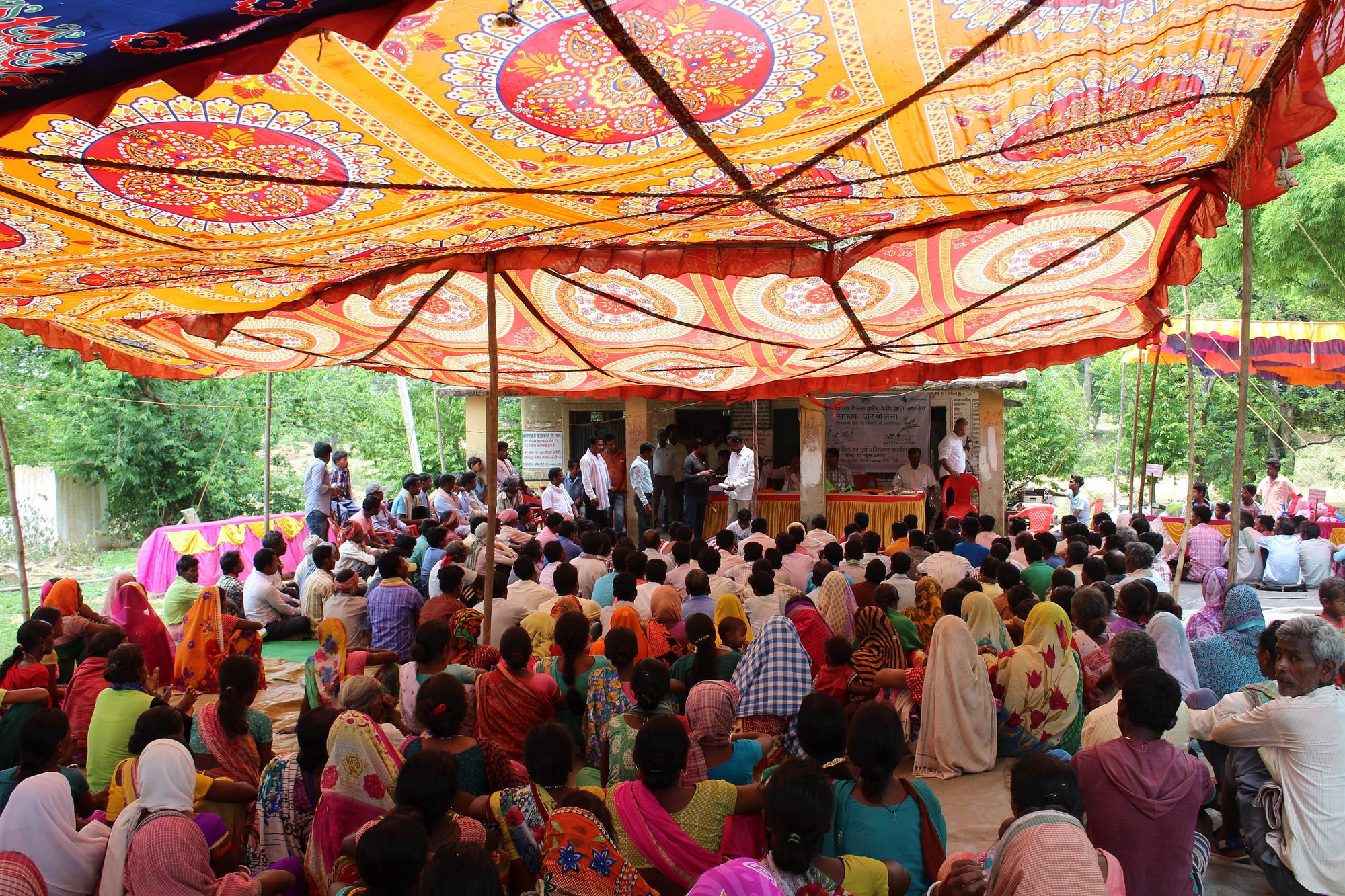 Farmers gathered under a tent to collect their bags of high-yielding rice seeds. / Neha Khator, USAID