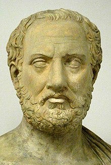 A stone bust of a man with a curly beard.