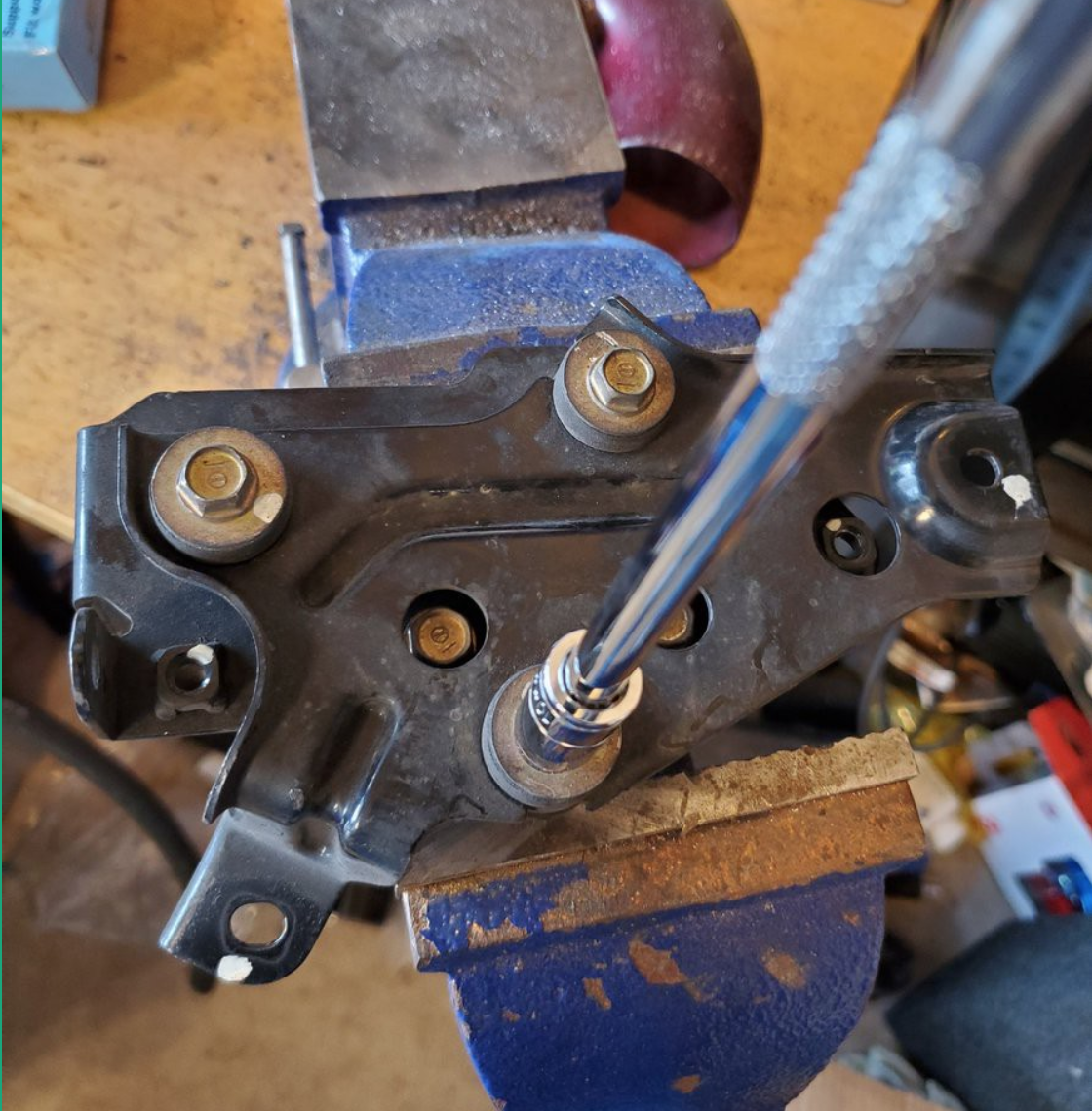 Bracket in vice with socket on bolt about to be removed.