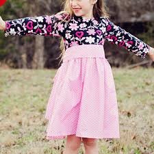 A little girl in a flowery long-sleeved shirt and a pink, flowy skirt