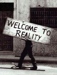 A black and white photography of a man carrying a big sign where you can read: "welcome to reality".