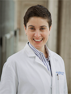 Dr. Juno Obedin-Maliver headshot wearing a white lab coat and blue striped color shirt underneath.