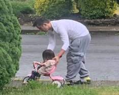 Dad protectively walking daughter on tricylce