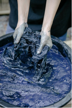 A person carefully removing a stain from a blue tablecloth with a cleaning solution