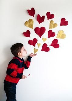 Create a cute valentine’s day photo shoot with the kids with a paper heart background on the wall