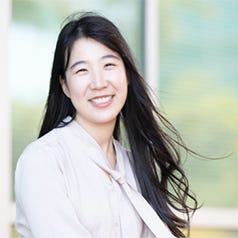 Kristina Wang — a woman with long dark hair and white top smiling