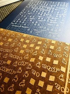 Photo of a series of squares and symbols that appear embossed in wood and imprinted onto a black surface.