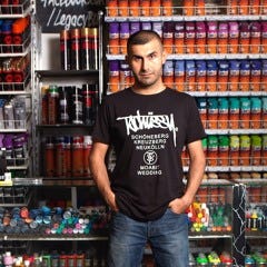 Owner of Legacy standing in front of the display of spray cans.