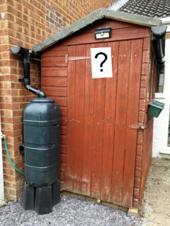 An English back-garden shed, with a question mark on it.