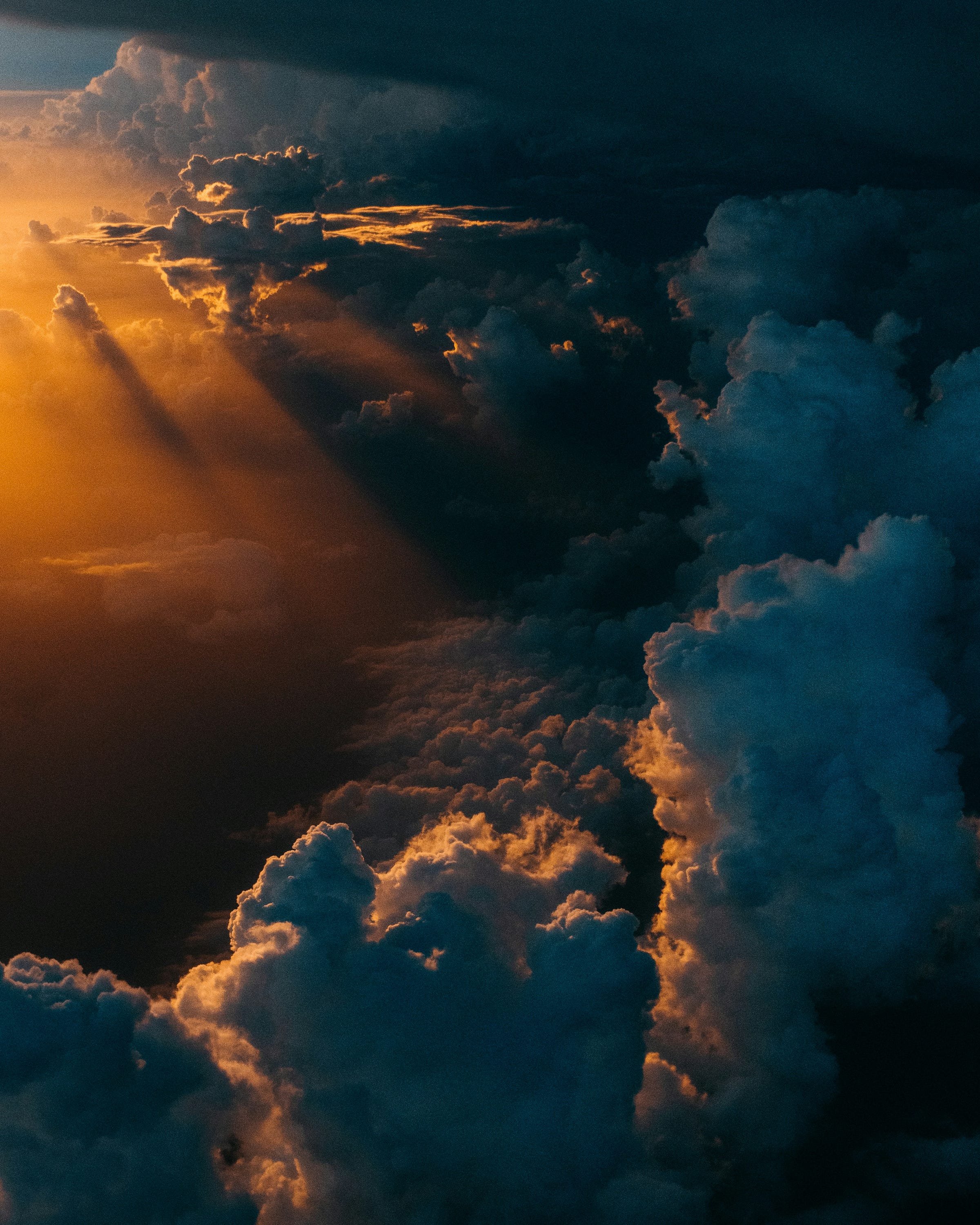 A photo of the sky. The sun stains the sky with its brightest golden smile and the sun shines through the dark, gloomy clouds.