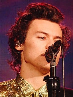 Close up of Harry’s face singing into mic, purple background
