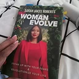 A hand holding a copy of the book: woman evolve