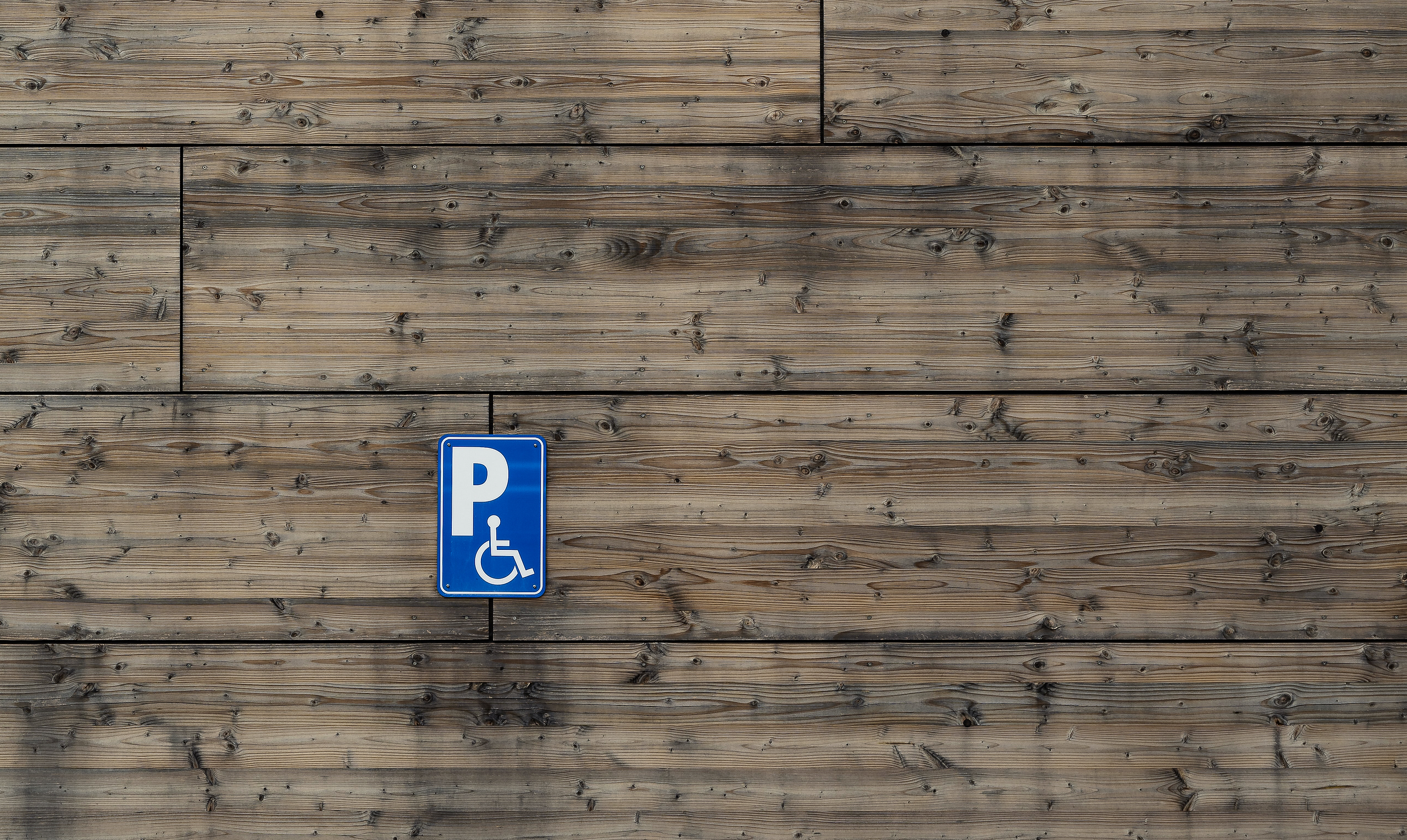 A decorative image for this article showing a disability-parking sign stuck on a wood/timber wall.
