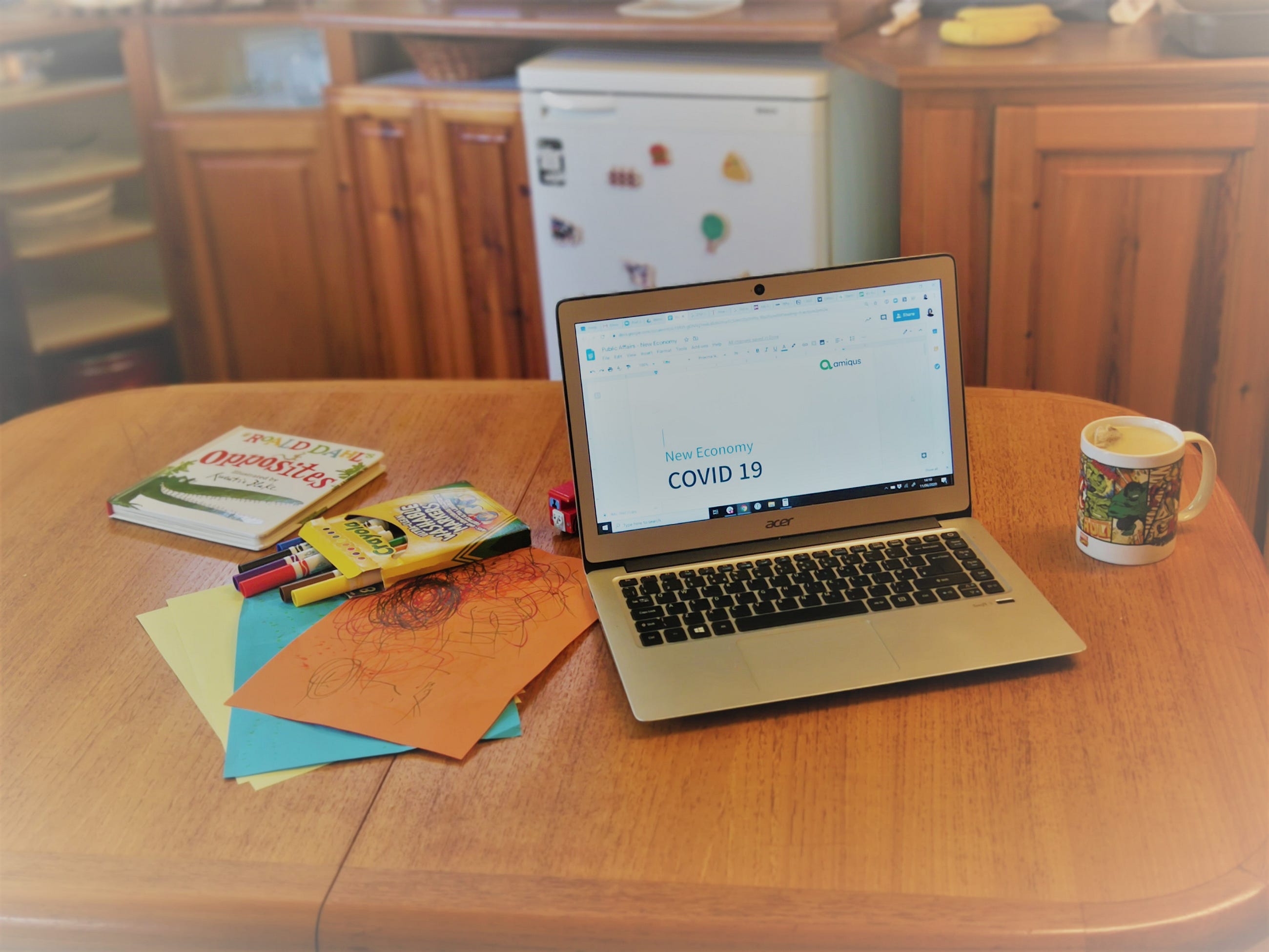An image taken of an employees work desk with a laptop desktop screen showing a document stating 'New Economy COVID-19'
