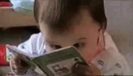 Baby with a book close to their face trying to read it.