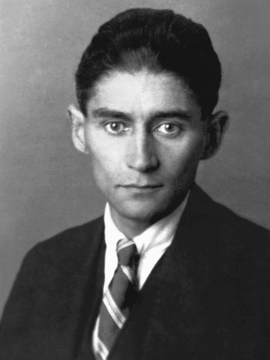 A imagem é o retrato em preto e branco de Kafka vestindo terno. Nele, mostra o rosto, a gravata e o colarinho do autor. Ele está posando dentro de casa contra uma parede.