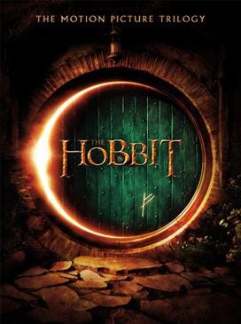 The cover for the Hobbit trilogy DVDs. A green door to a hobbit hole, the door is cracked open with a light shining through. A mark is on the door towards the bottom. Text reads “The Hobbit” across the center of the door.