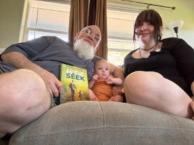 Author, his daughter, and her son on couch with copy of Hide and Seek memoir in hand