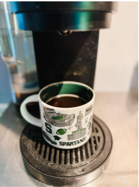 A Michigan State Spartans coffee cup in a single-serve coffee maker.