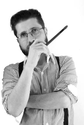Imagem de Gustavot Diaz em preto e branco. O artista segura um pincel na mão.