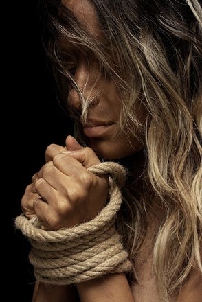 Blonde woman clutching a rope, bondage implications