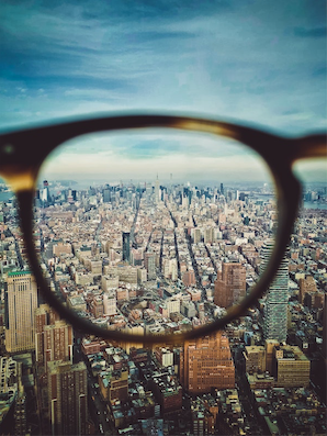 Looking at a vast city-scape through a pair of reading glasses