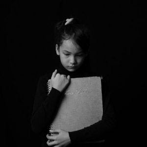 Child holding photo album and being emotional