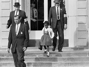 Ruby Bridges (a young Black girl) walking down steps of school flanked by three white US Marshals.