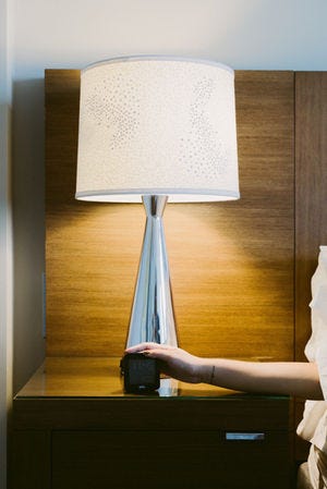 A large lamp and some reaching over to turn off the alarm clock on the bedside table.