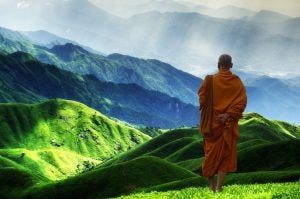 Buddhist monk on hill overlooking mountains