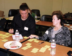 Volunteer alums Alice and Dave brainstorm ideas on sticky notes for HPVANDME, a client of the Solutions Lab.