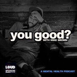 A black man checking his phone with his hand to his head with the podcast title “You Good” with Mike Brown” overlaid in white