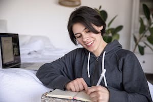 A lady writing in a notebook and happy