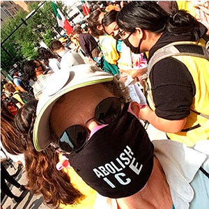 person wearing Abolish ICE mask with other people in background