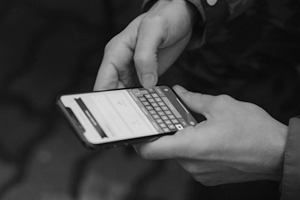 Close-up of someone typing into a Blackberry.