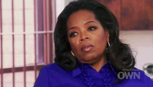 Oprah staring and looking something up and down with a very stern displeased look on her face.