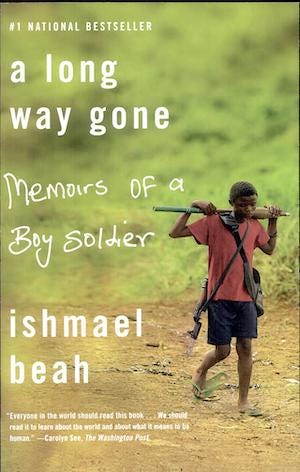 This is an image of the cover of the book “A Long Way Gone: Memoirs of a Boy Soldier” by Isnmael Beah. The image shows a young boy wearing torn shoes and dirty clothing carying a weapon over his shoulders. He is walking alone down a dirt path by a grassy hill.