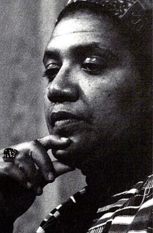 I gritty picture of Audre Lorde looking contemplative with her index finger resting on her chin.