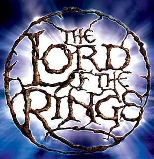 Logo for The Lord of the Rings Musical. Text reads “The Lord of the Rings” in a circle designed to look like tree branches with a ring in the center, the background is blue with a white light shining through.