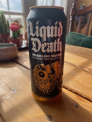 Black can of sparkling Liquid Death on a wooden table.