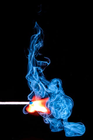 blue flame of a match lit against a black background