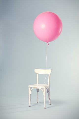 white chair with a pink balloon tied to it.