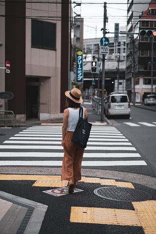 A woman with her back to the camera crosses a street in Tokyo