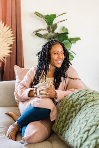Woman on couch holding coffee cup and smiling