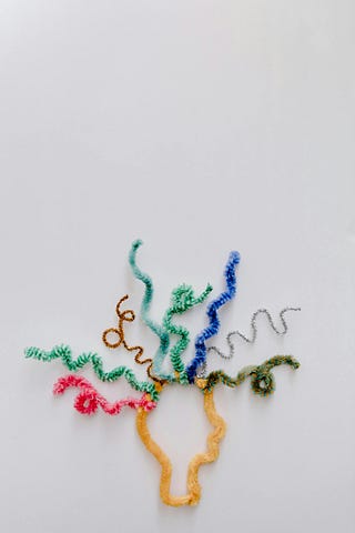 White background using pipe cleaners to show the outline of a head with different colours and shapes of pipe cleaners representing hair