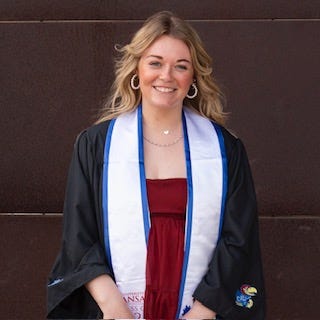 A woman wearing a black graduation gown and stole over a red dress.
