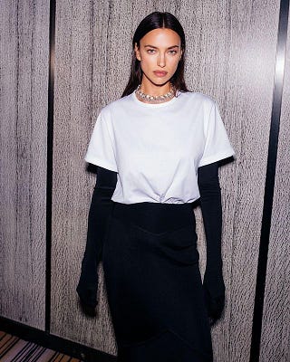 Irina Shayk in a white t shirt, black skirt and gloves at a Swarovski event.