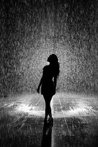 Silhouette of woman in white shower of rain on a road.