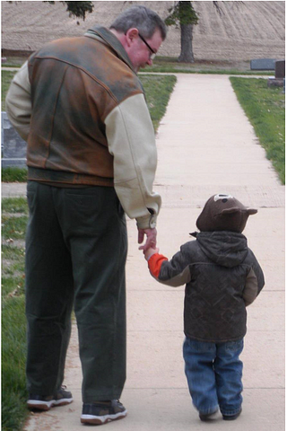 A Grandfather and grandson walking in cemetery.